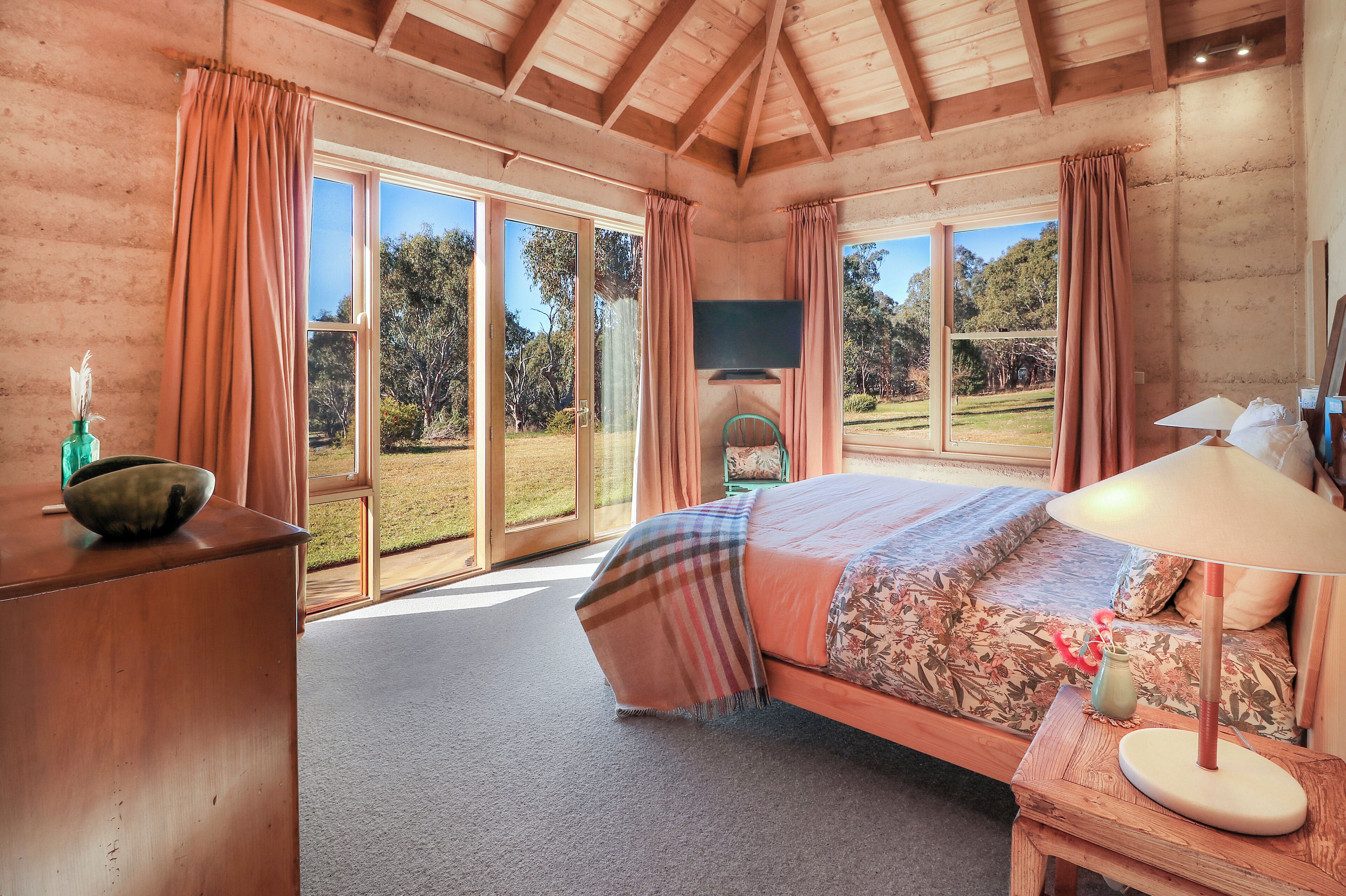 A bedroom with a large bed, a television, and a view of the outdoors.