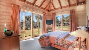 A bedroom with a large bed, a television, and a view of the outdoors.