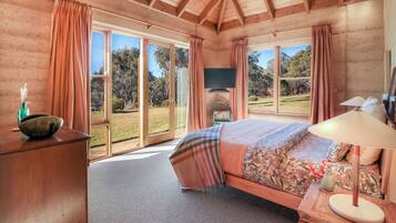 A bedroom with a large bed, a television, and a view of the outdoors.