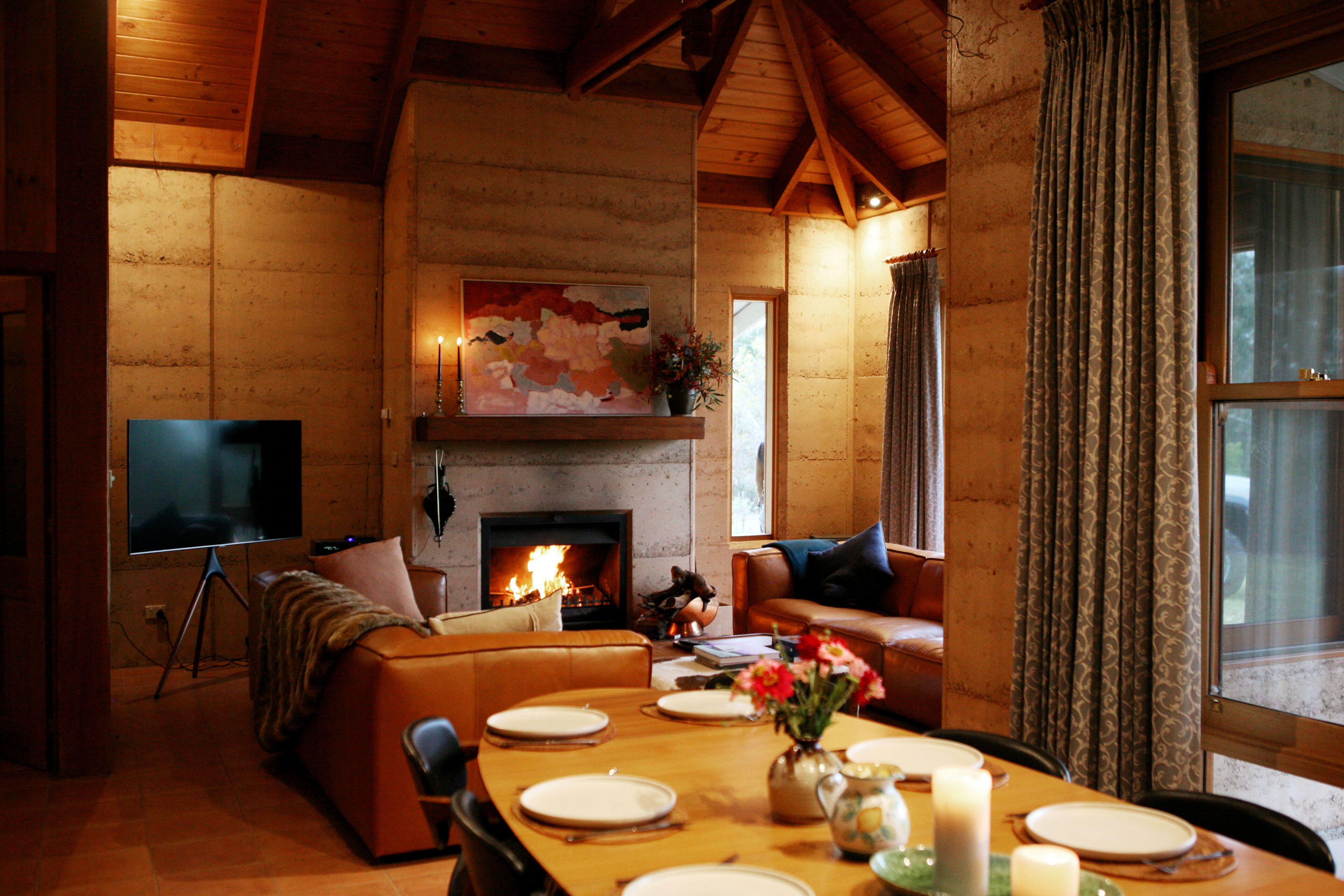 A cozy living room with a fireplace, a television, and a dining area set for four.