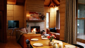 A cozy living room with a fireplace, a television, and a dining area set for four.