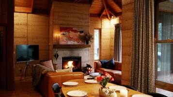 A cozy living room with a fireplace, a television, and a dining area set for four.