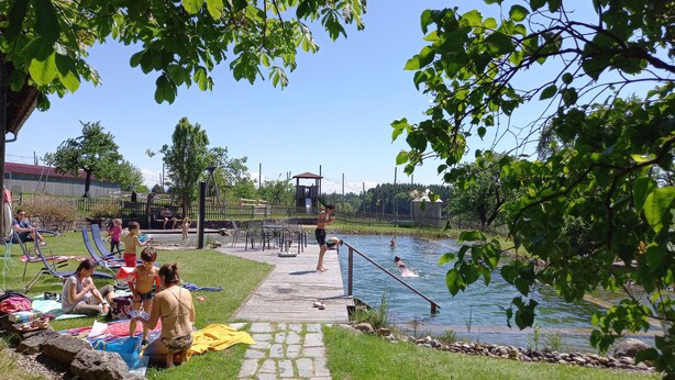 A swimming pool area with a wooden deck, lounge chairs, and a lifeguard tower.