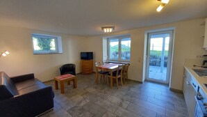 A compact living space with a dining area, a television, and a kitchenette.