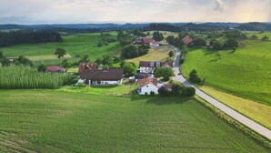 A rural landscape with a winding road, green fields, and scattered houses.