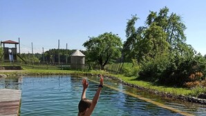 A child jumping into a swimming pool surrounded by a wooden deck and a fence.