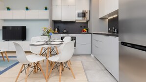 Une cuisine moderne avec des meubles blancs, un four à micro-ondes encastré et un réfrigérateur en acier inoxydable.