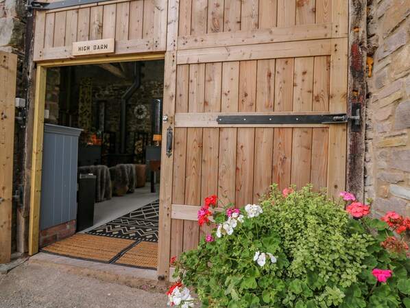 A wooden door with a sign reading "HIGH BARN" and a doormat with a black and white pattern. - Pen Bont Home Farm (Brecon)