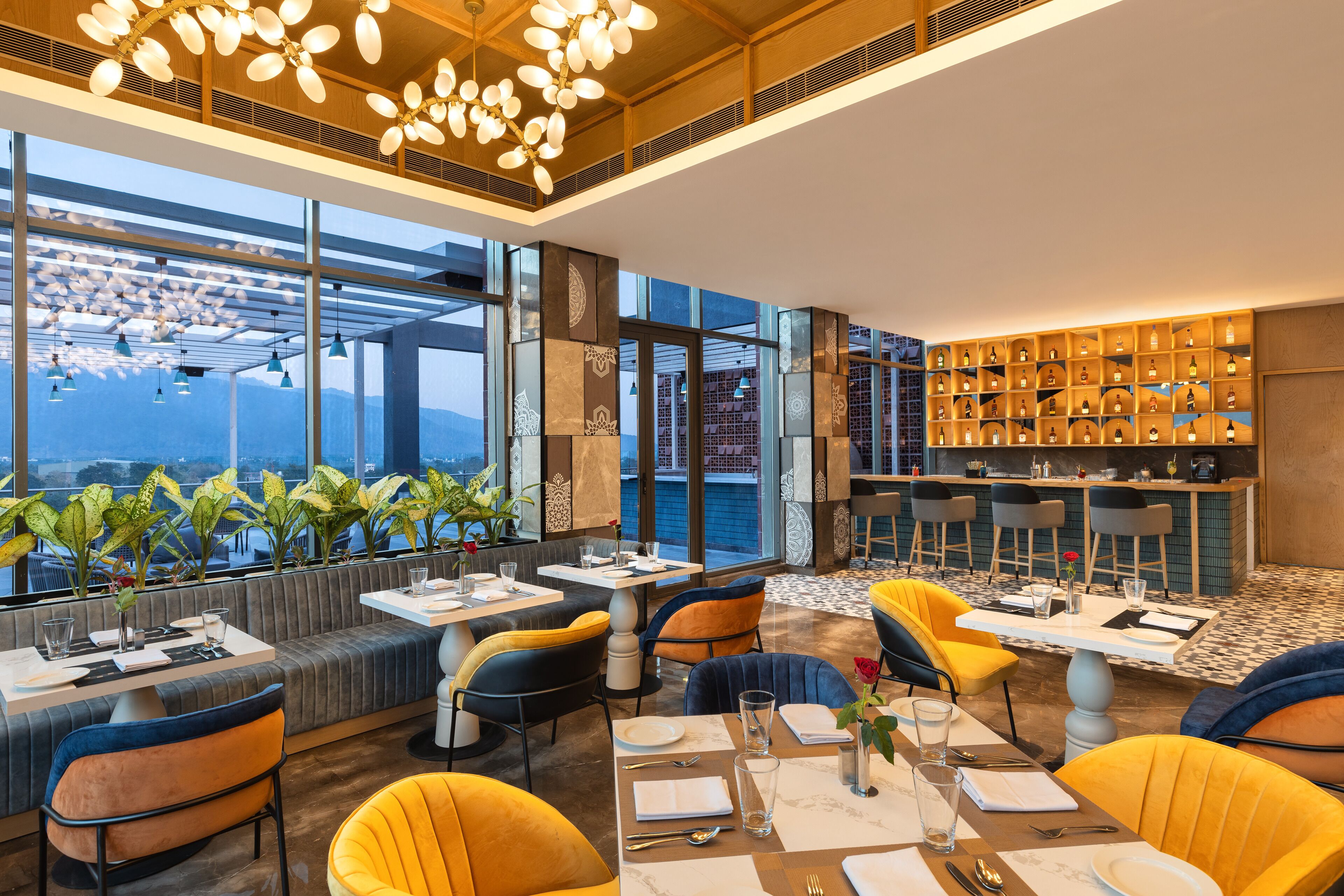 Un restaurante moderno con techo alto, ventanas amplias y diferentes opciones de asientos, incluyendo cabinas y mesas.