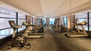 Un gimnasio moderno con diversas máquinas de cardio, ventanas amplias y un diseño espacioso.