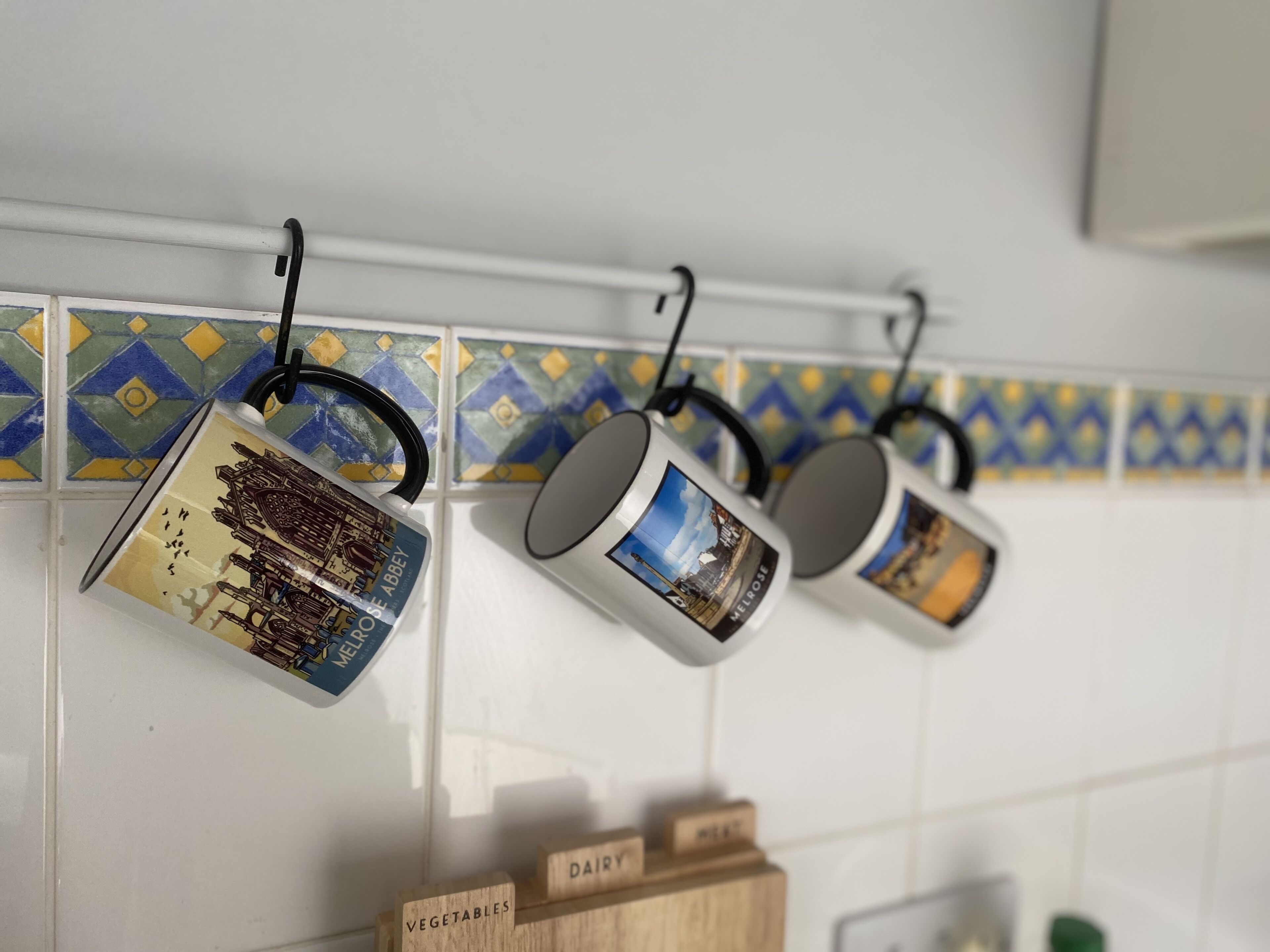 Kitchen utensils hanging on a rack with a tiled backsplash.