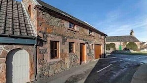 A stone building with a tiled roof, a wooden door, and a small window. - The Stables Cottage (Darnick)