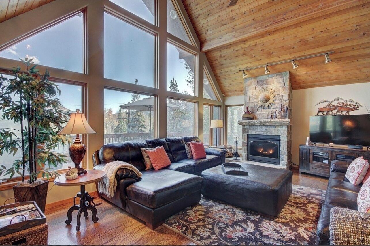 A spacious living room with a fireplace, large windows, and a cozy seating area.
