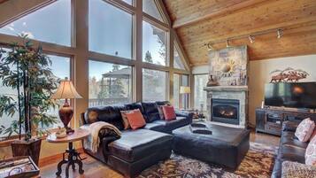 A spacious living room with a fireplace, large windows, and a cozy seating area.