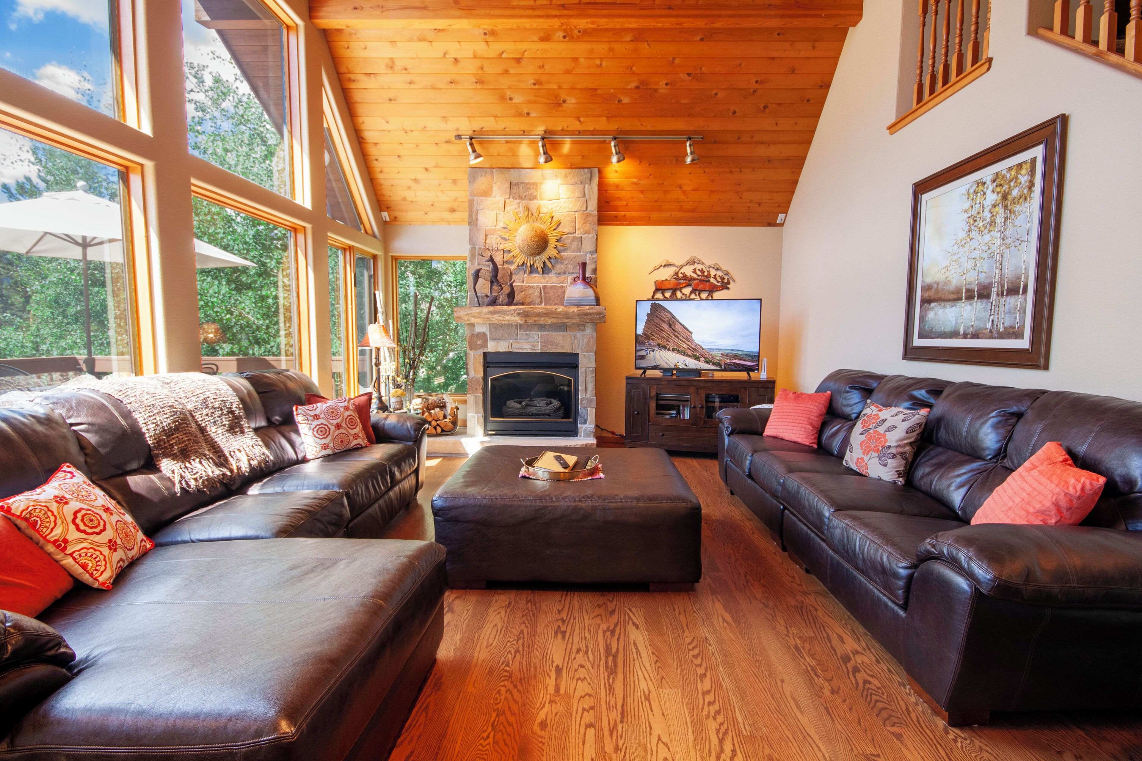 A spacious living room with leather sofas, a fireplace, and a television.