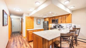 A modern kitchen with wooden cabinets, a central island with bar stools, and built-in appliances.