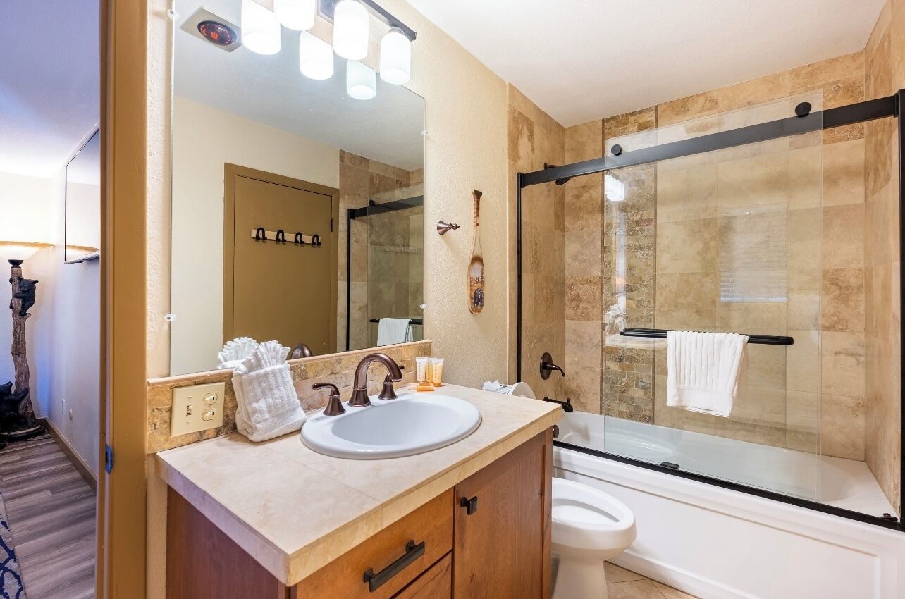 Une salle de bain moderne avec un grand miroir, un lavabo et une douche à parois de verre.