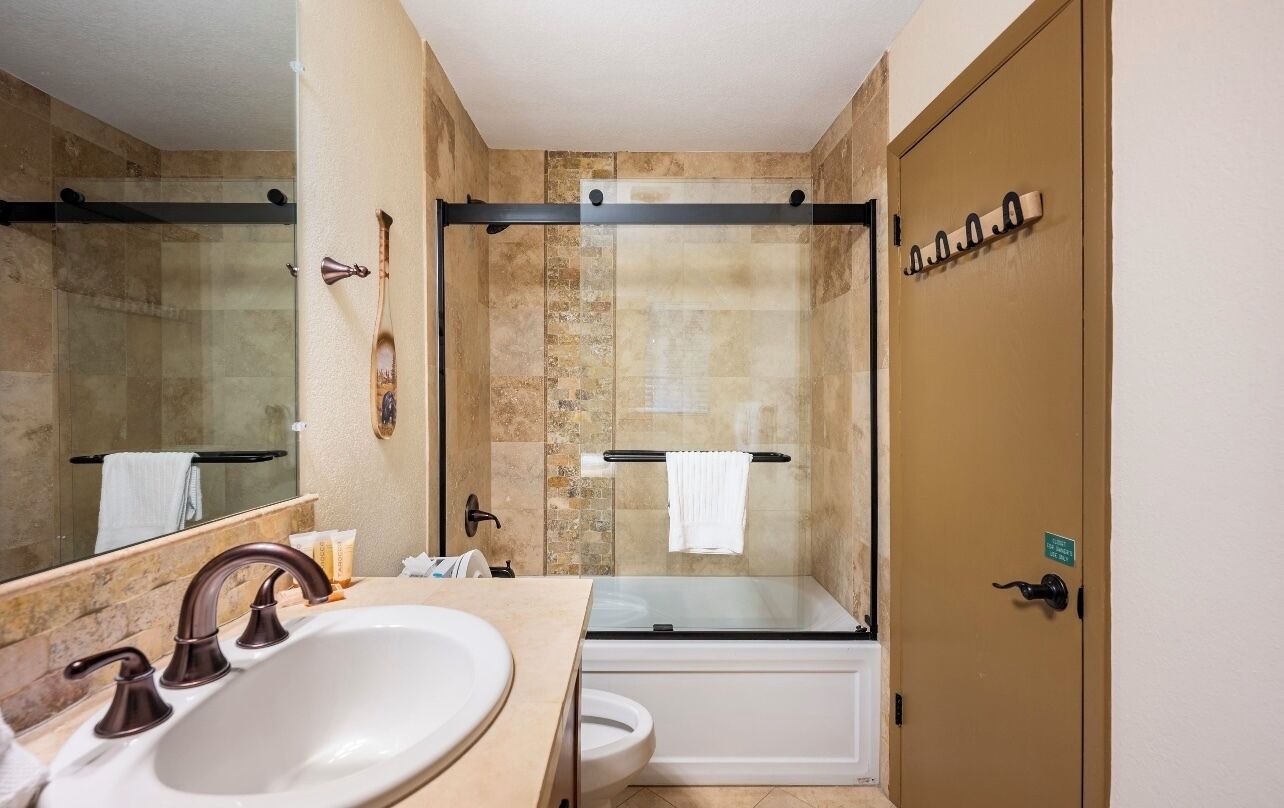 Een badkamer met een wastafel, spiegel, douche en toilet.
