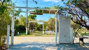Ein verschlossenes Tor mit einer Pergola, einer Bank und einem Metallgitter.
