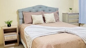 Ein Schlafzimmer mit einem Bett, Nachttischen, einer Kommode und drei an der Wand befestigten Hüten.