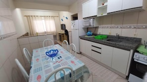 Une cuisine compacte avec des meubles blancs, un four à micro-ondes, un évier et une table à manger avec des chaises.