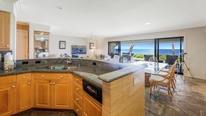 A kitchen with granite countertops, wooden cabinets, a dishwasher, and a large island.
