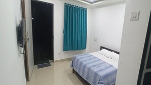 A bedroom with a bed, a wardrobe, and a curtain. - Starlight Resort (Alibag)