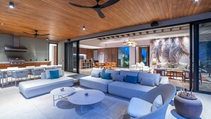 Een ruime woonkamer met een modern design, voorzien van een grote bank, een salontafel en een eethoek met een tafel en stoelen.