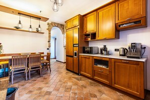 A kitchen with wooden cabinets, a microwave, a coffee maker, and a dining area with chairs and a table.