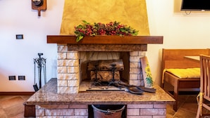 A stone fireplace with a wooden mantel, a metal poker, and a bucket underneath. - Villa "L'antica Lugana" with lake view, balconies, and Wi-Fi (Sirmione)