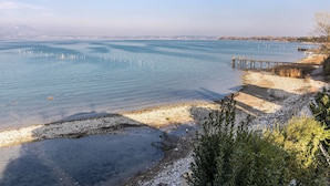 A coastal landscape with a pier extending into calm waters, a sandy beach, and sparse vegetation. - Villa "L'antica Lugana" with lake view, balconies, and Wi-Fi (Sirmione)