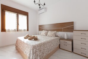 Un dormitorio con cama, mesitas de noche, armario, ventana con cortinas y equipo de aire acondicionado.
