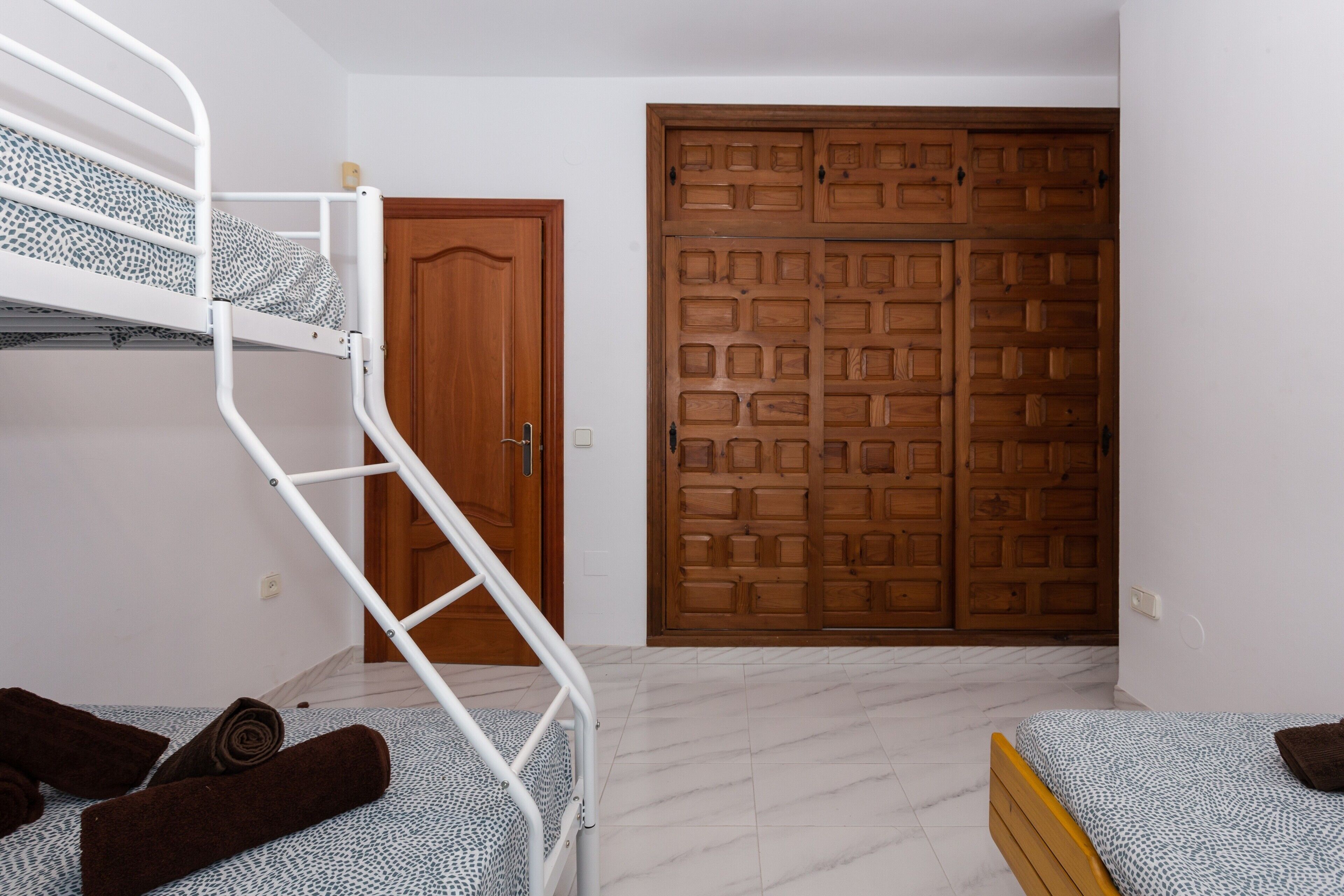 Une pièce avec un lit superposé, une armoire en bois et une porte.