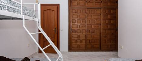 Une pièce avec un lit superposé, une armoire en bois et une porte.