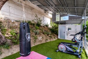 A home gym with a punching bag, exercise equipment, and a small shed.