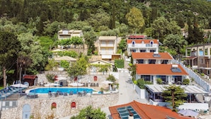 A hillside hotel with a swimming pool, multiple balconies, and a mountainous backdrop. - Studio Apartment "Chakalaka 7" with Sea View, Shared Pool & Wi-Fi (Leykada)