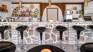 A bar area with stone walls, black bar stools, and a variety of bottles on shelves. - Studio Apartment "Chakalaka 6" with Sea View, Shared Pool & Wi-Fi (Leykada)