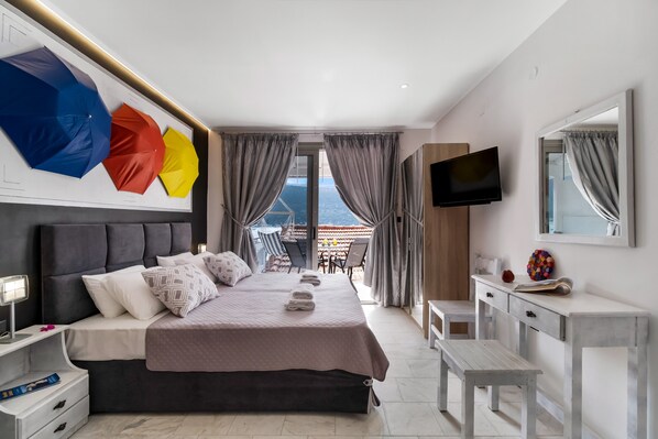 A modern hotel room with a bed, bedside table, TV, and a balcony with curtains.