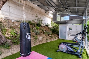 A home gym with a punching bag, exercise equipment, and a small shed.