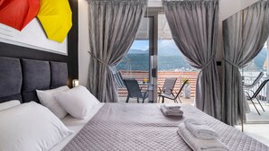 A hotel room with a bed, grey curtains, a balcony with a table and chairs, and a mountain view. - Studio Apartment 'Chakalaka with Sofa Bed 15' with Sea View, Wi-Fi and Air Conditioning (Leykada)