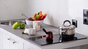 Una cocina moderna con estufa integrada, un bol de verduras, una tetera y un lavabo.
