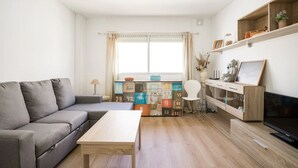 Una sala de estar con un sofá, una mesa de centro, un televisor y una estantería con cajas de almacenamiento numeradas.