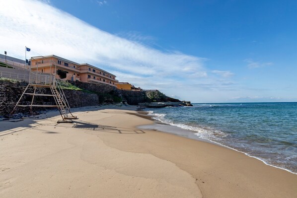 A beach with a building, a ladder, and a flag.
