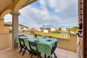 A balcony with a table set for dining, a view of the sea, and surrounding buildings. - Holiday Home "Villa Pitti" with Sea View, Terraces & Wi-Fi (Castelsardo)