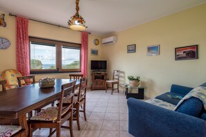 A dining area with a wooden table and chairs, a television, and a sofa. - Holiday Home "Villa Pitti" with Sea View, Terraces & Wi-Fi (Castelsardo)