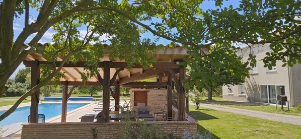 A pool area with a pergola, outdoor seating, and a stone structure.