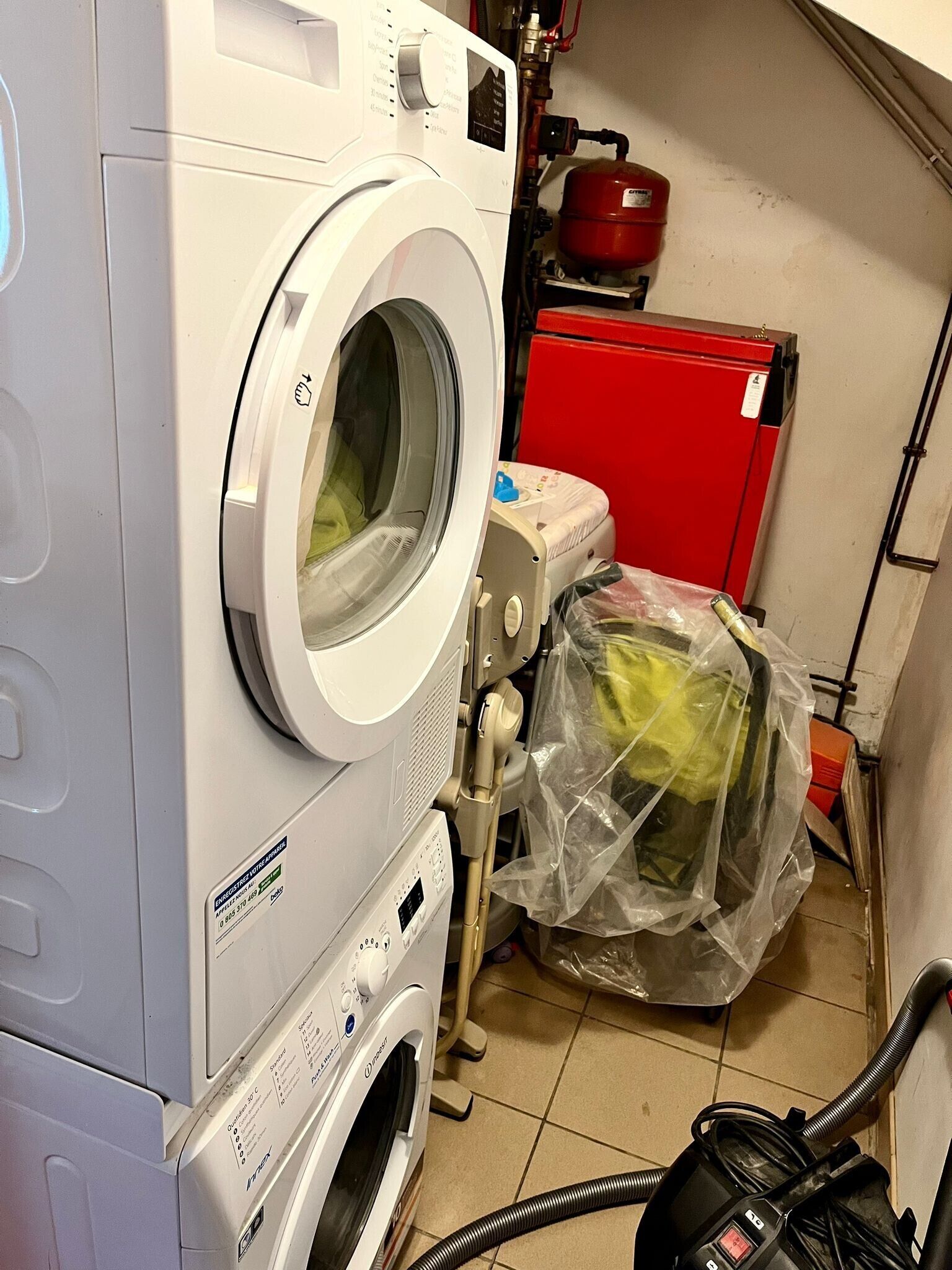 Een wasserette met een voorlader wasmachine, een droger en een rode inpandige kast.