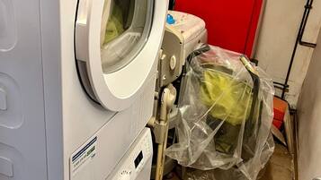 Een wasserette met een voorlader wasmachine, een droger en een rode inpandige kast.