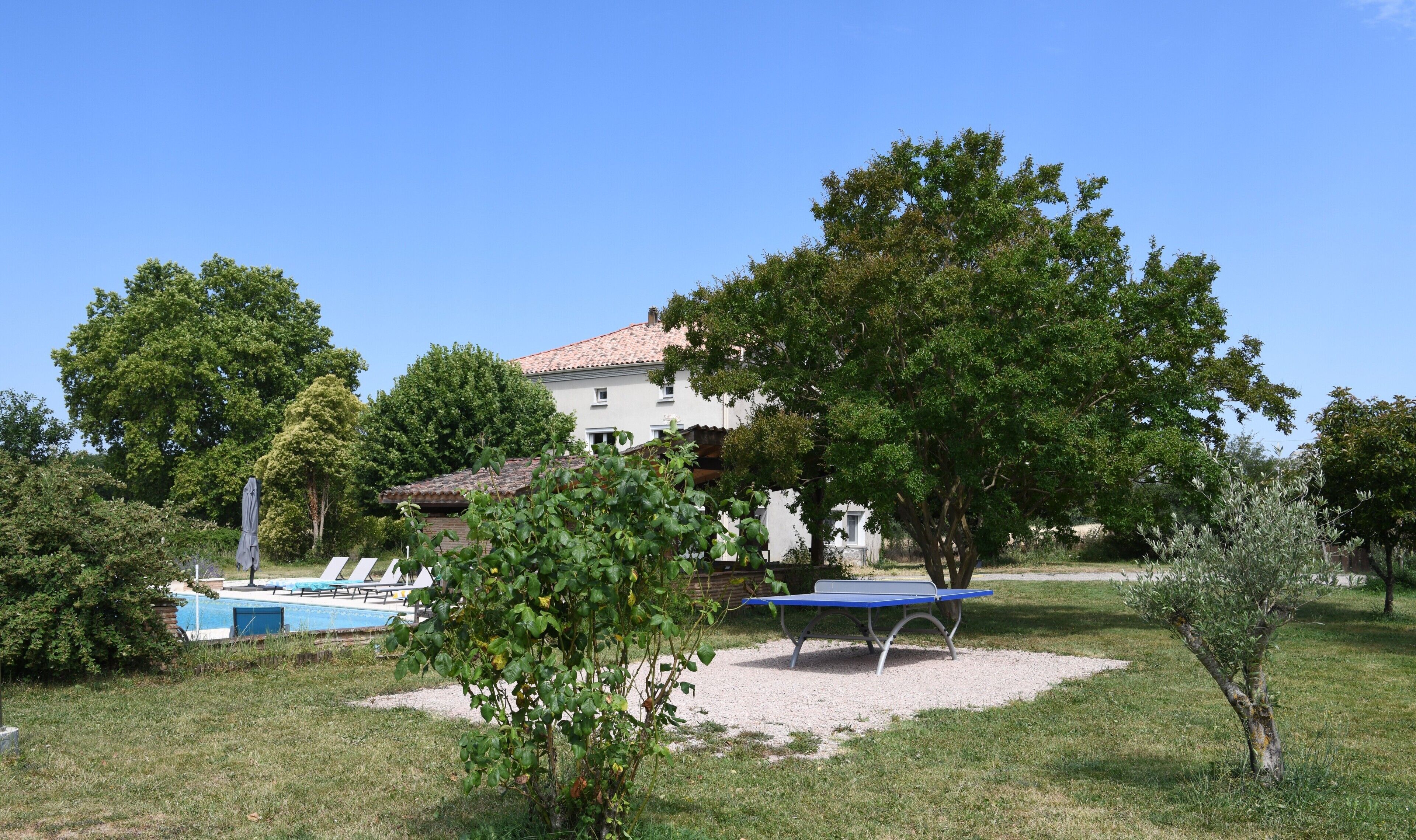Eine Villa mit Swimmingpool, einer Terrasse mit Liegestühlen und einem Spielbereich.