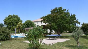 Eine Villa mit Swimmingpool, einer Terrasse mit Liegestühlen und einem Spielbereich.